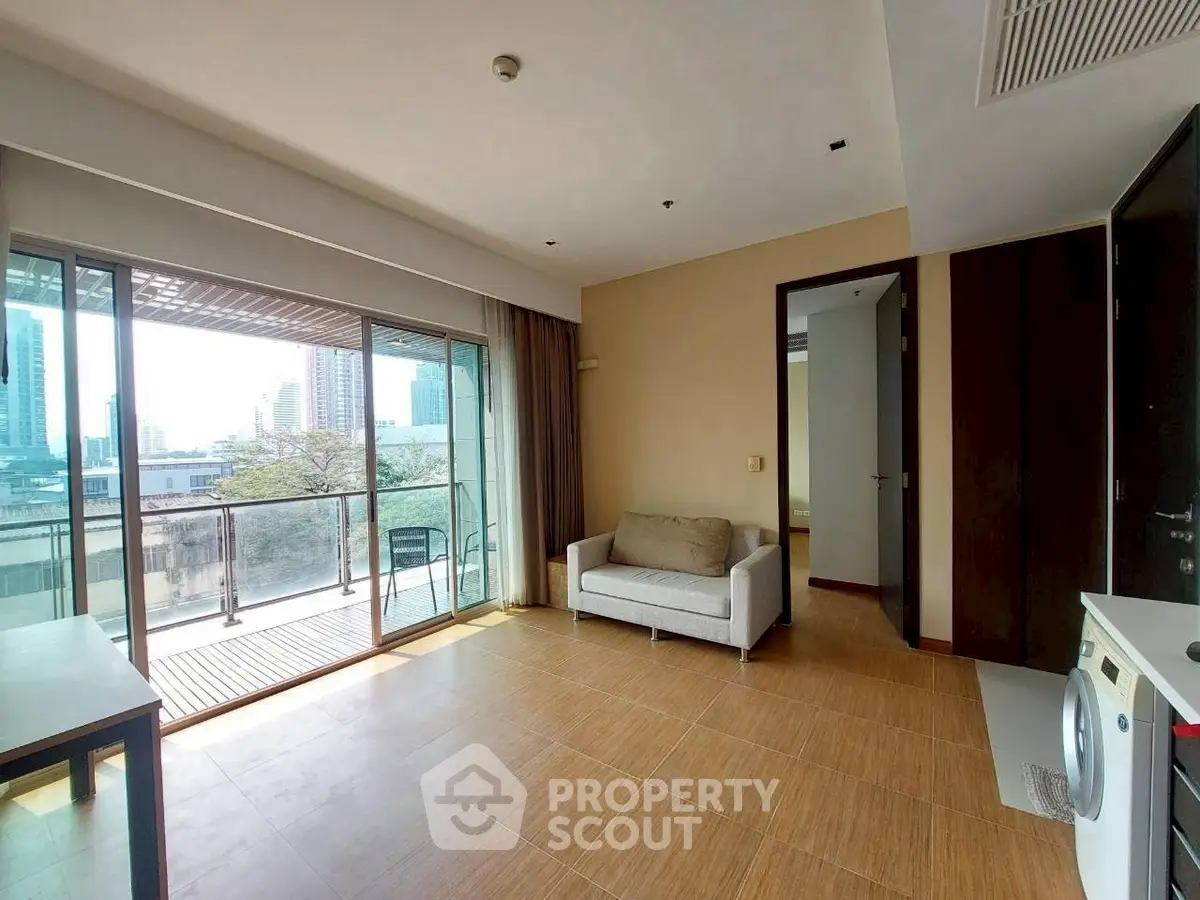 Spacious living room with balcony and city view, featuring modern furniture and washing machine.