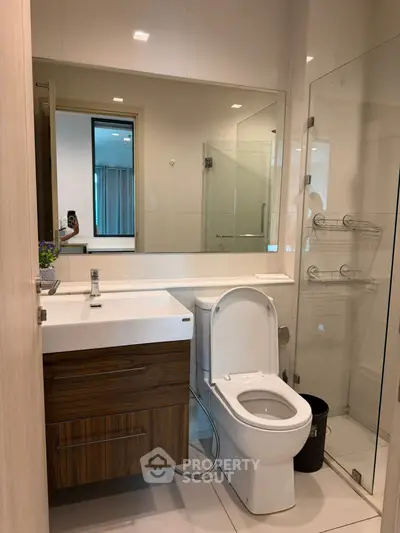 Modern bathroom with sleek fixtures and glass shower enclosure in a contemporary apartment.