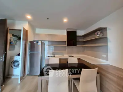 Modern kitchen with sleek cabinetry, dining area, and built-in appliances in a stylish apartment.
