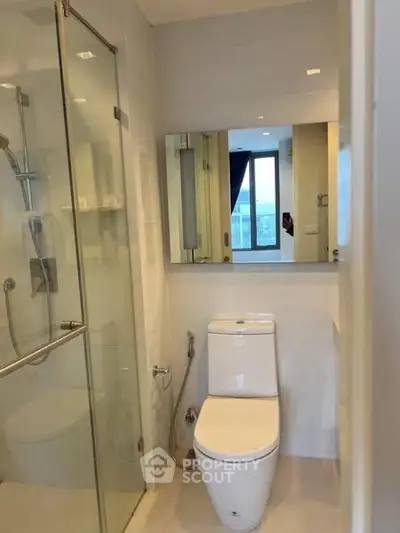 Modern bathroom with glass shower and sleek fixtures in a bright apartment.
