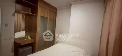 Cozy bedroom with wooden wardrobe and dressing table, perfect for relaxation.