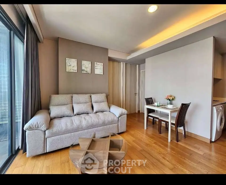 Modern living room with cozy sofa and dining area, featuring wooden flooring and natural light.