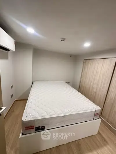 Modern bedroom with minimalist design featuring a comfortable bed and sleek wooden flooring.