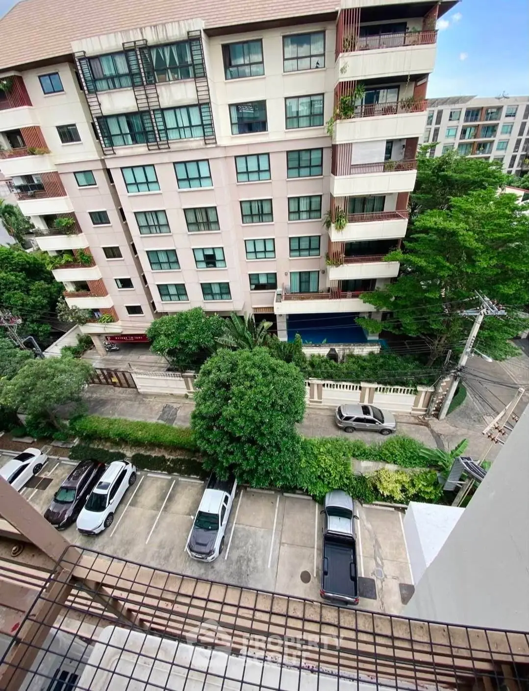 High-rise building view with parking area and lush greenery