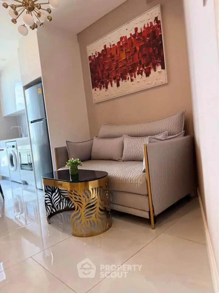 Modern living room with stylish sofa, abstract art, and sleek kitchen appliances in a contemporary apartment.
