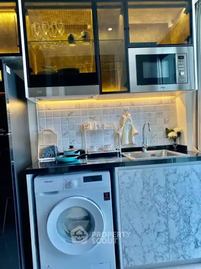 Modern kitchen with marble accents, built-in appliances, and washing machine.