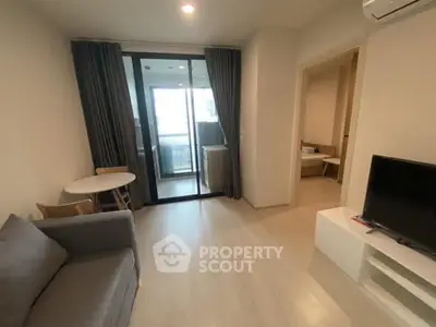 Modern living room with balcony access, featuring sleek furniture and natural light.