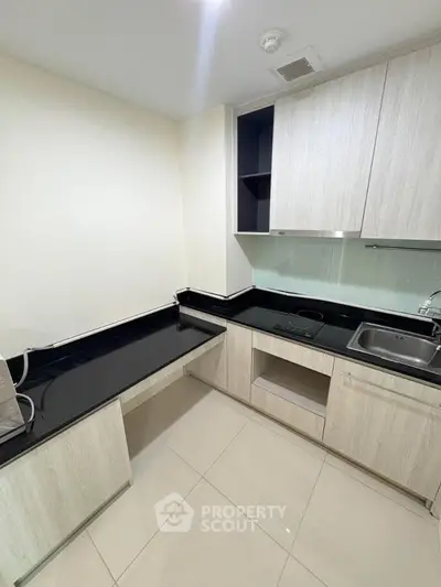 Modern kitchen with sleek black countertops and light wood cabinetry