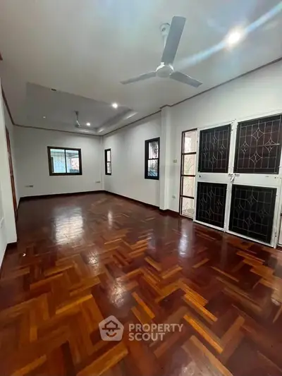 Spacious living room with elegant wooden flooring and ceiling fan in modern apartment.