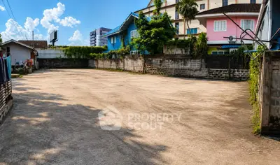 Spacious outdoor area with potential for development, surrounded by colorful residential buildings.