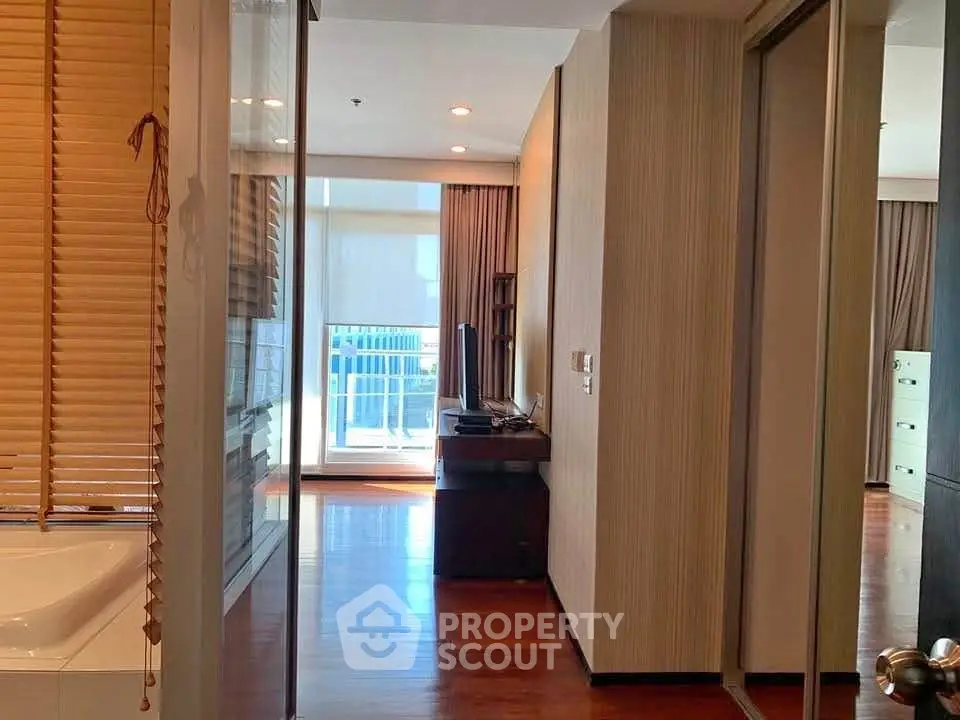 Modern apartment hallway with wooden flooring and balcony view, featuring sleek design and natural light.