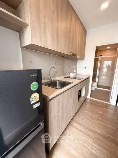 Modern kitchen with sleek wooden cabinetry and stainless steel appliances in a stylish apartment.