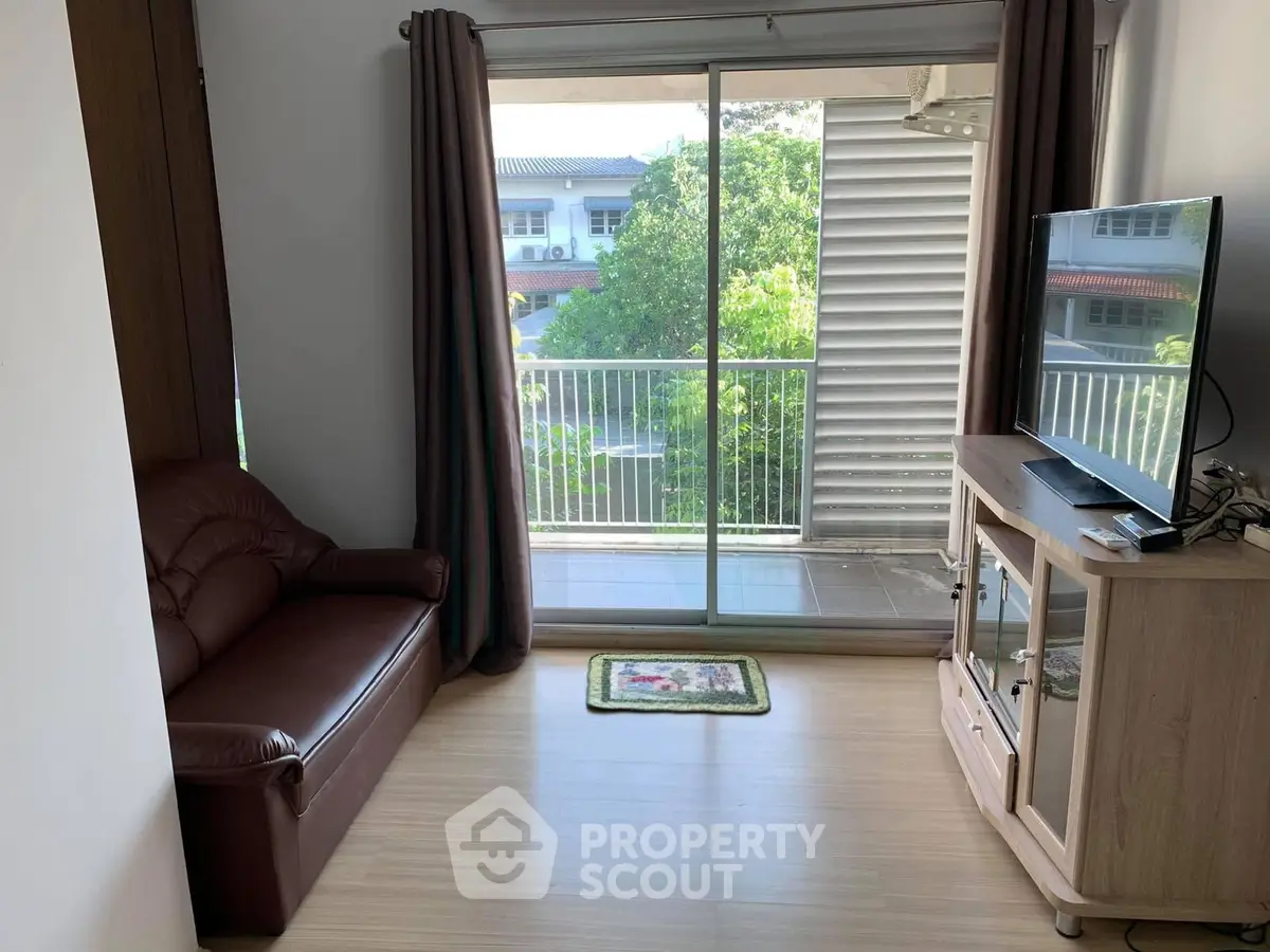 Cozy living room with balcony view, featuring a leather sofa and modern TV stand, perfect for relaxation.