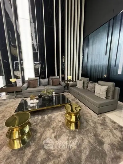 Luxurious modern living room with sleek gray sofas and stylish gold accent tables.