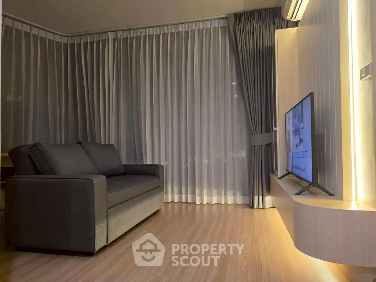 Modern living room with sleek sofa and wall-mounted TV, featuring elegant floor-to-ceiling curtains.