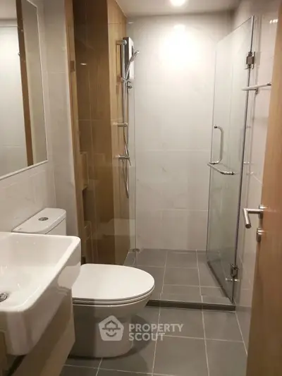Modern bathroom with glass shower and sleek fixtures in contemporary apartment.
