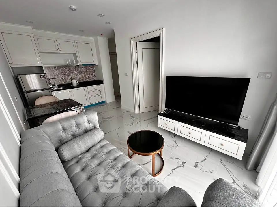 Modern living room with sleek kitchen, stylish sofa, and large TV, perfect for urban living.
