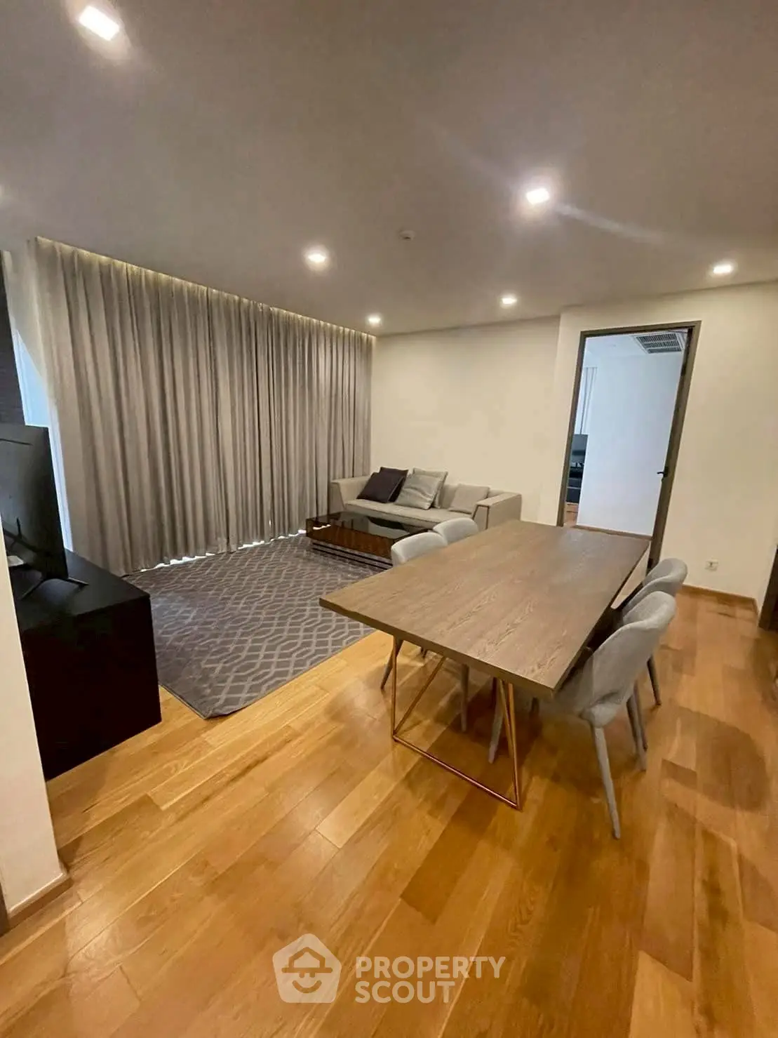 Modern living room with wooden flooring, cozy sofa, and dining area in open layout.