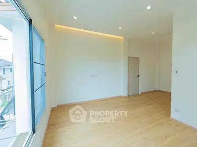 Spacious empty room with large window and wooden flooring in modern home