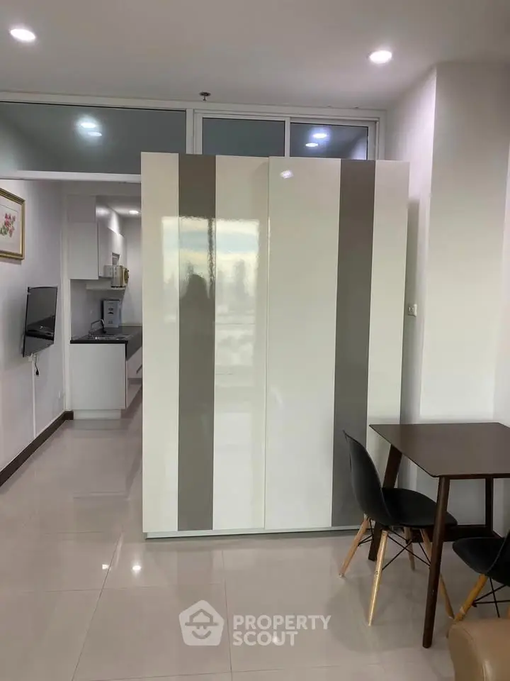 Modern apartment interior with sleek kitchen and dining area, featuring contemporary furniture and glossy finishes.