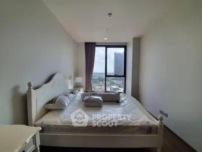 Spacious bedroom with large window offering stunning city views in modern apartment.
