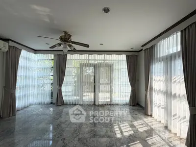 Spacious living room with marble flooring and large windows for natural light.