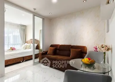Modern living room with brown sofa and glass table, adjacent to a cozy bedroom with elegant decor.