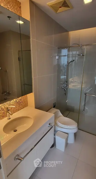Modern bathroom with glass shower and elegant vanity in upscale apartment.