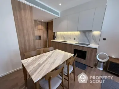 Modern kitchen with sleek wooden cabinetry and dining area in contemporary apartment.