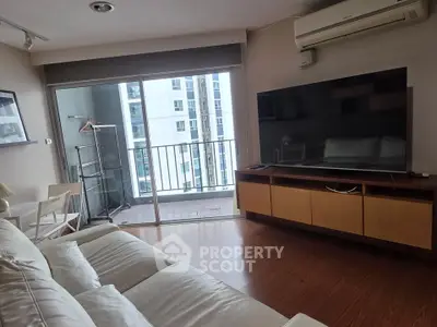 Modern living room with large TV and balcony view in high-rise apartment