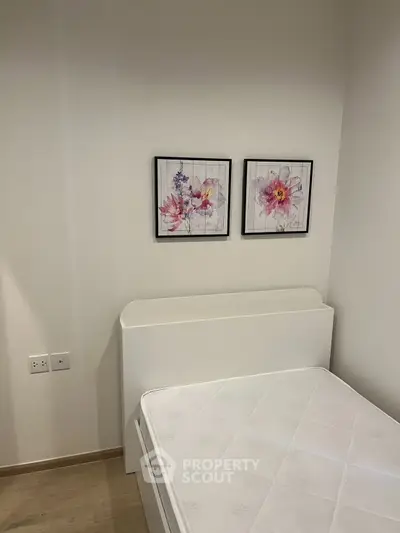 Cozy bedroom with minimalist decor and floral artwork, perfect for a serene living space.