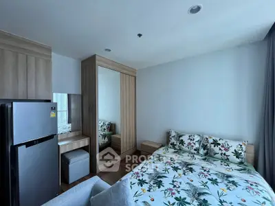 Modern bedroom with floral bedding, mirrored wardrobe, and compact fridge in a stylish apartment.