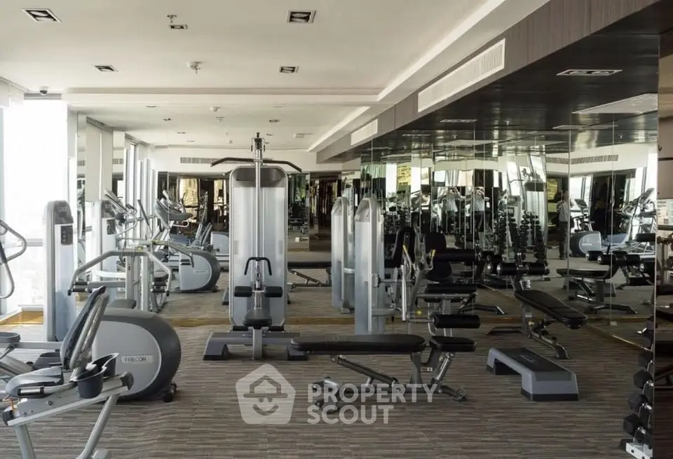 Modern gym with state-of-the-art fitness equipment and mirrored walls in a luxury residential building.