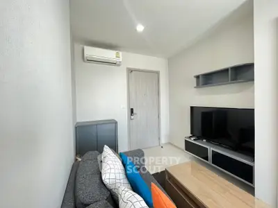Modern living room with sleek furniture and wall-mounted TV in a cozy apartment.