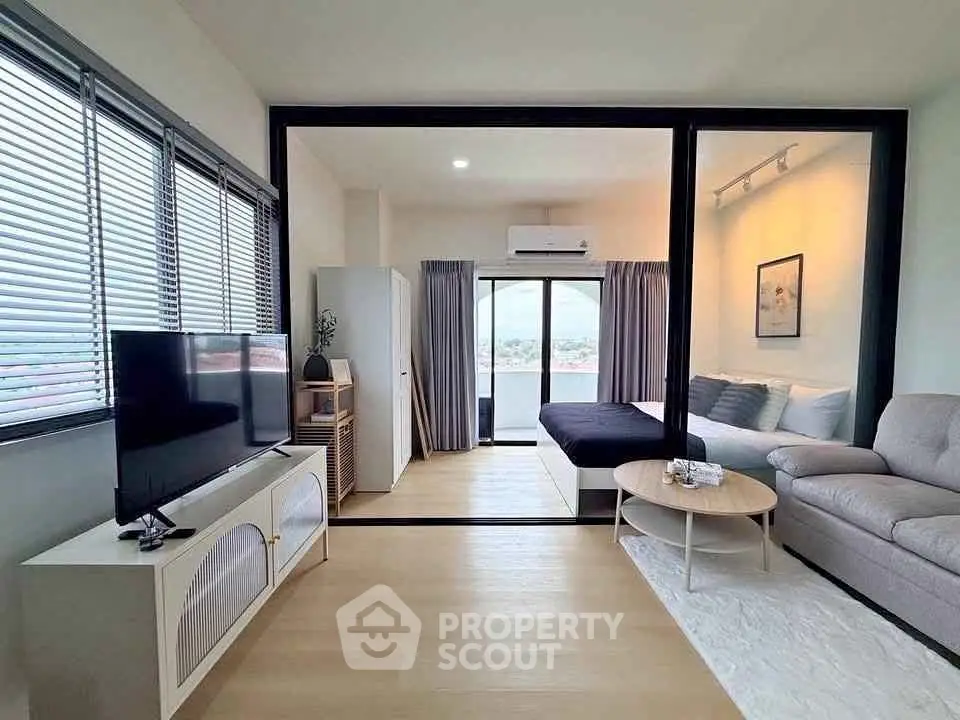 Modern living room with open layout and stylish decor, featuring a cozy seating area and large windows.