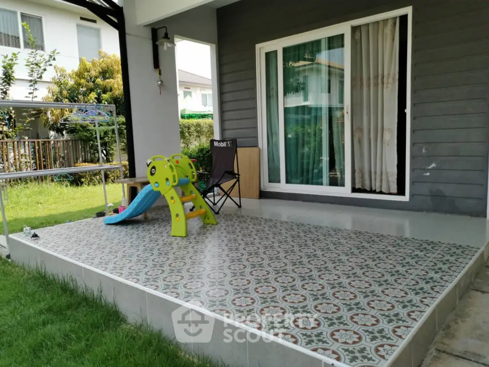 Charming patio with playful slide and lush garden view, perfect for family relaxation.
