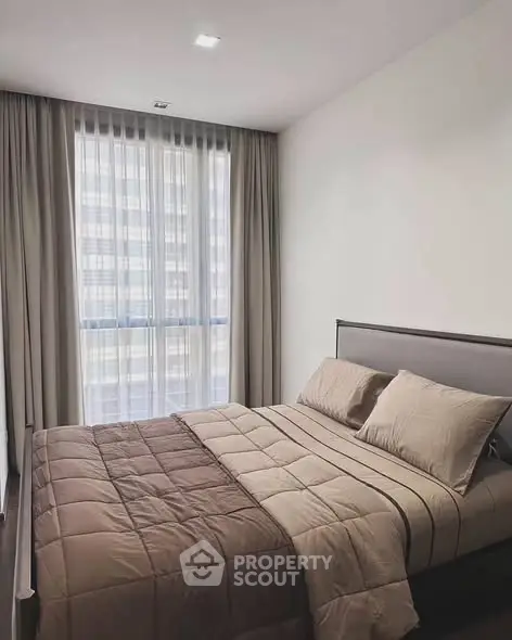 Modern bedroom with large window and elegant curtains in a stylish apartment.