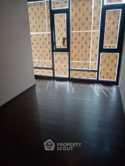 Spacious empty room with large windows and wooden flooring, perfect for customization.
