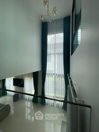 Spacious modern living room with high ceilings and elegant floor-to-ceiling windows.