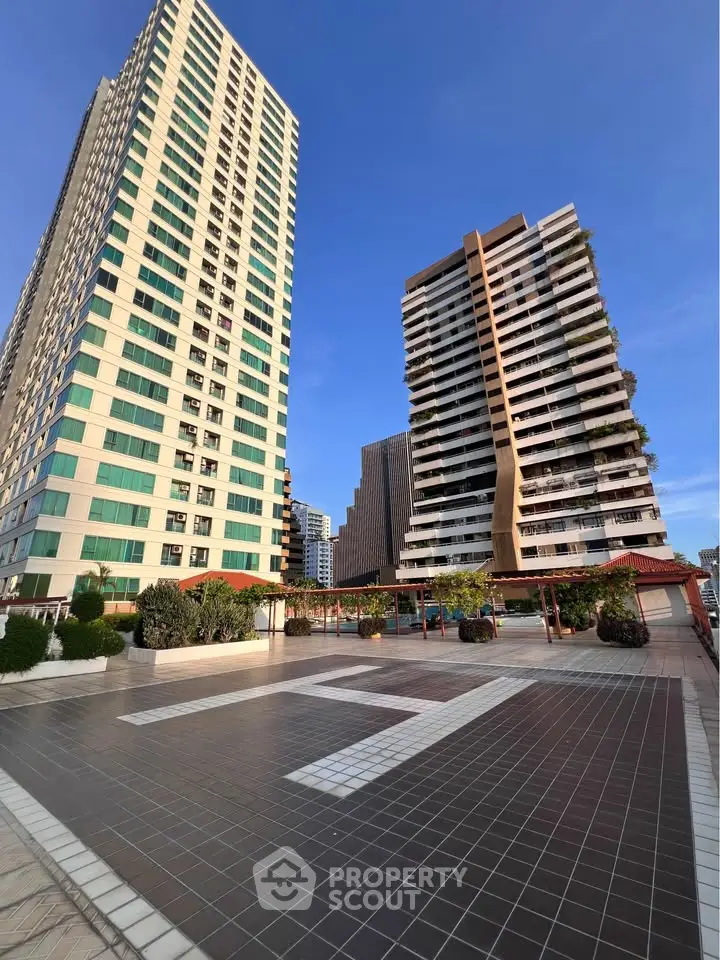 Stunning high-rise residential buildings with spacious outdoor terrace and clear blue sky.