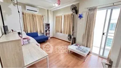 Spacious living room with wooden flooring, large windows, and modern furnishings.