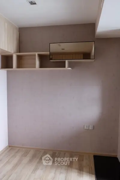 Modern minimalist room with wooden flooring and built-in shelving, ideal for versatile use.