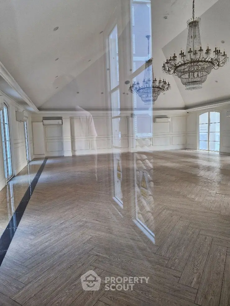 Spacious elegant room with chandeliers and large windows, perfect for luxury living.