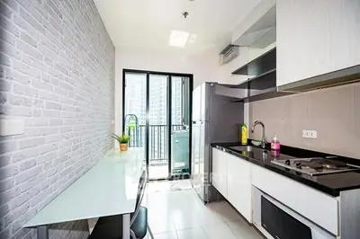 Modern kitchen with sleek design and balcony view in urban apartment.