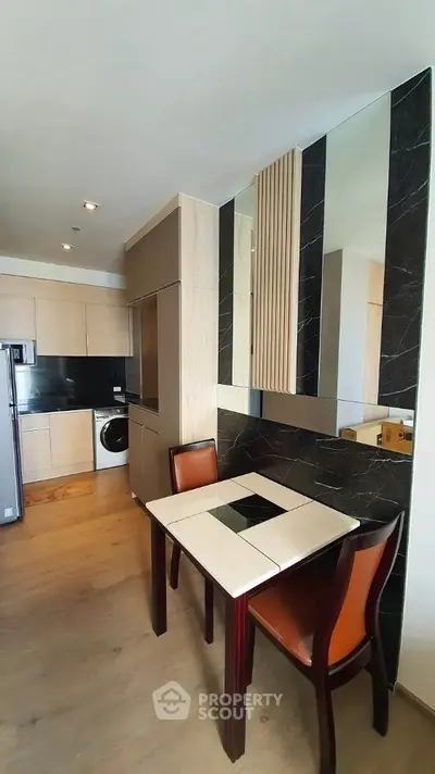 Modern kitchen with sleek appliances and compact dining area in stylish apartment.