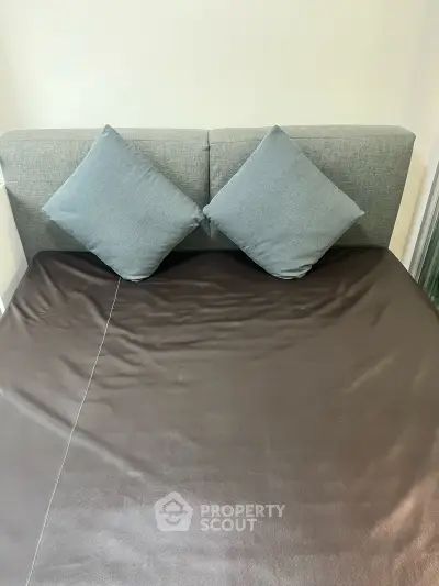 Cozy bedroom with modern grey headboard and plush pillows, perfect for relaxation.