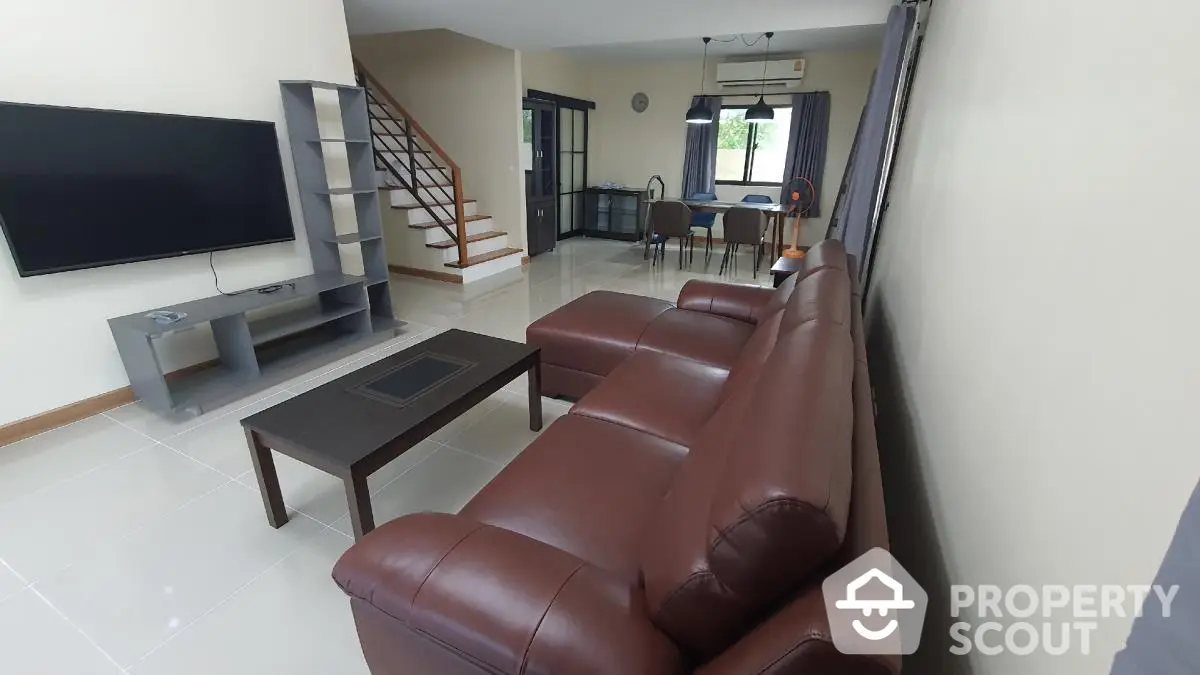 Spacious modern living room with leather sofa and large TV, open layout design.