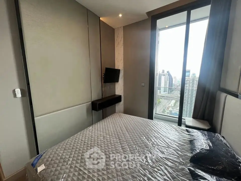 Modern bedroom with city view and sleek design in high-rise apartment.