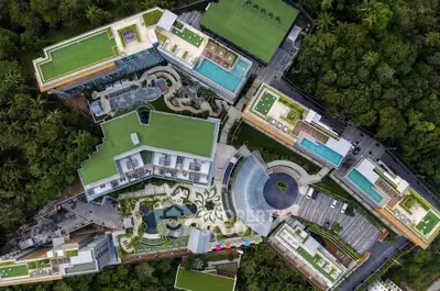 Aerial view of a luxurious modern residential complex with lush greenery and multiple pools.