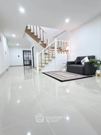 Modern living room with sleek staircase and glossy tiled flooring